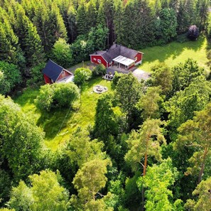 A red house with a large deck and a smaller red shed in a forested area. - Hazelnut Villa - Lake & Town Retreat (Osby)