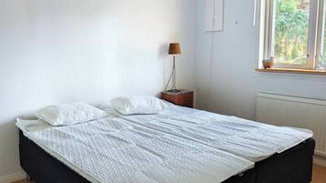 A bedroom with a large bed, a bedside lamp, a window with a view, and a ceiling light fixture.