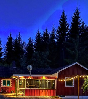 Um edifício vermelho com antena parabólica, grandes janelas e luzes de Natal.