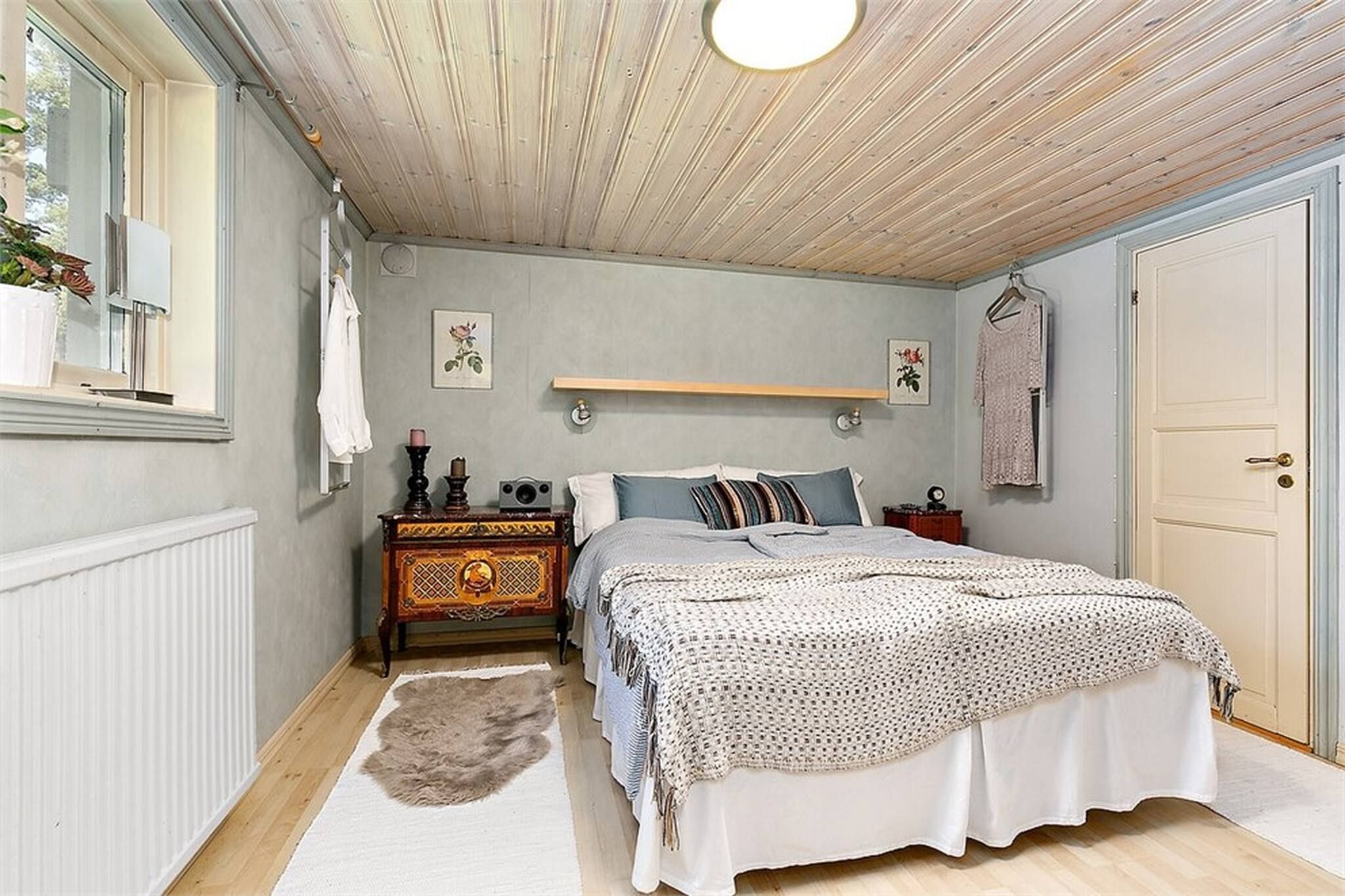 A bedroom with a bed, dresser, and a hanging light fixture.