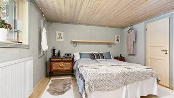 A bedroom with a bed, dresser, and a hanging light fixture.