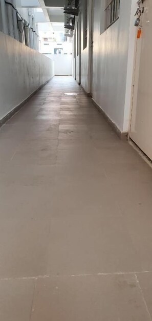 A long, narrow hallway with a tiled floor leading to a door at the end. - Hotel Ashiyana Inn (Patna)
