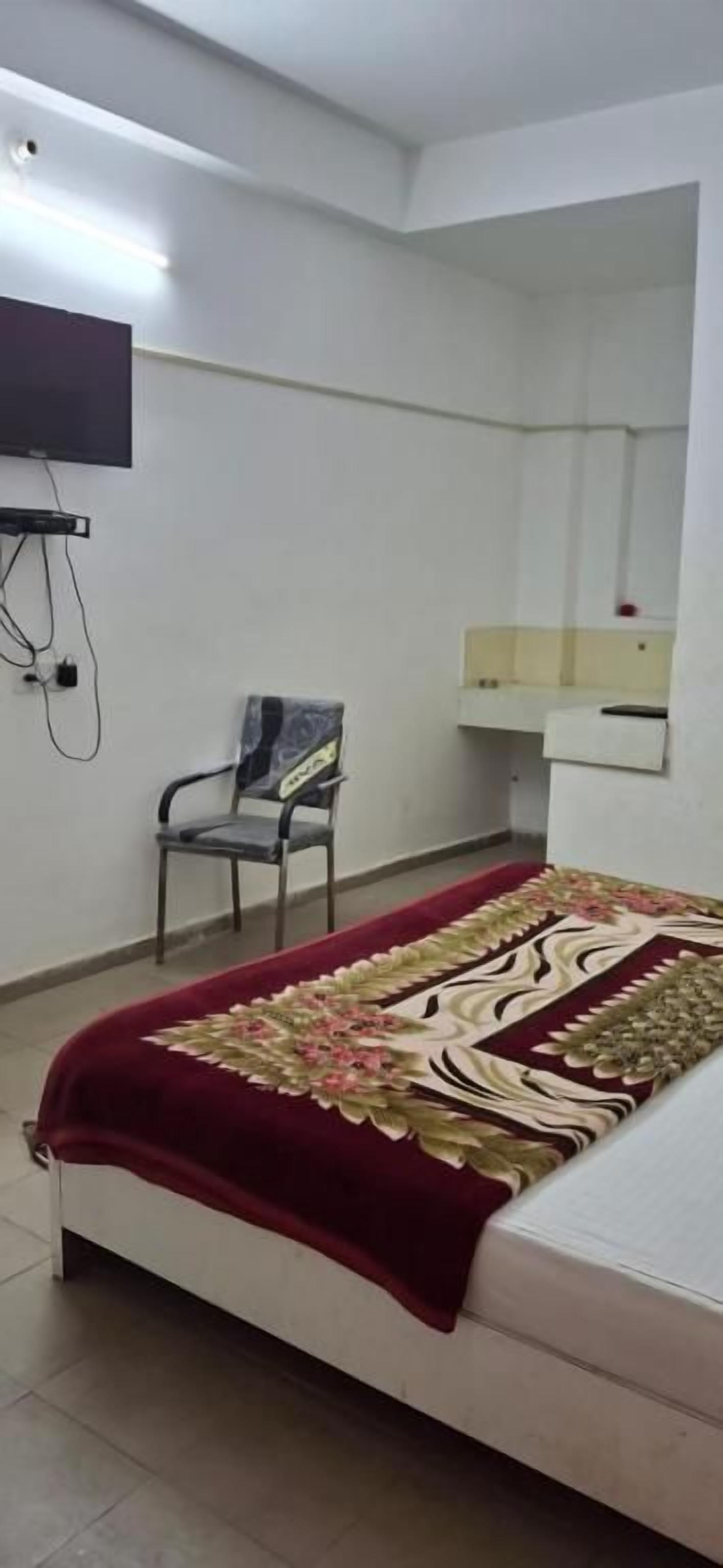Ein Schlafzimmer mit einem Bett, einem Sessel, einem an der Wand montierten Fernseher und einem Spiegel über dem Bett.