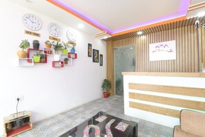 Un espace d’accueil avec un comptoir en bois, plusieurs horloges murales et des plantes en pot.
