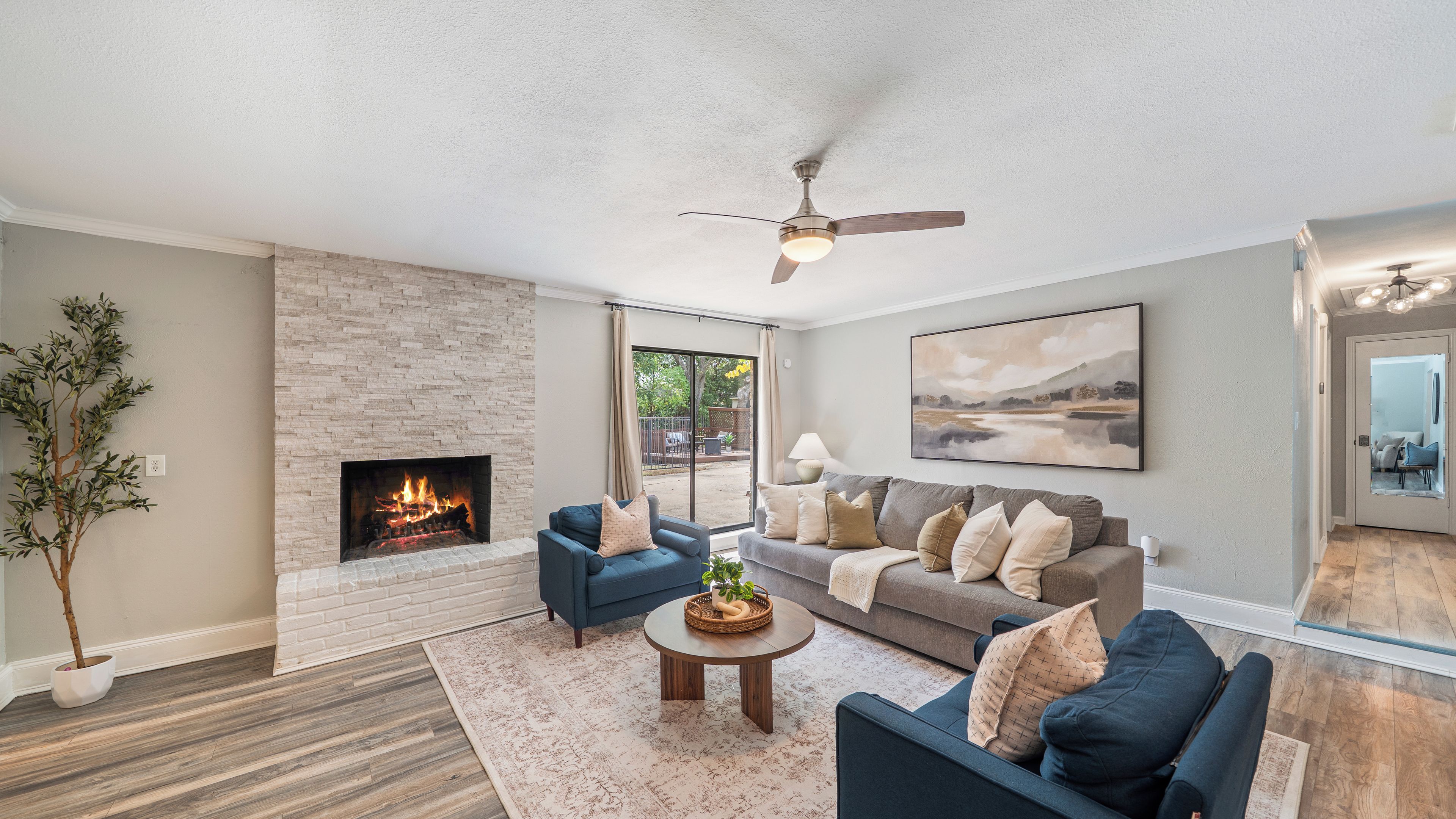 A living room with a fireplace, a ceiling fan, a sofa, and a coffee table.