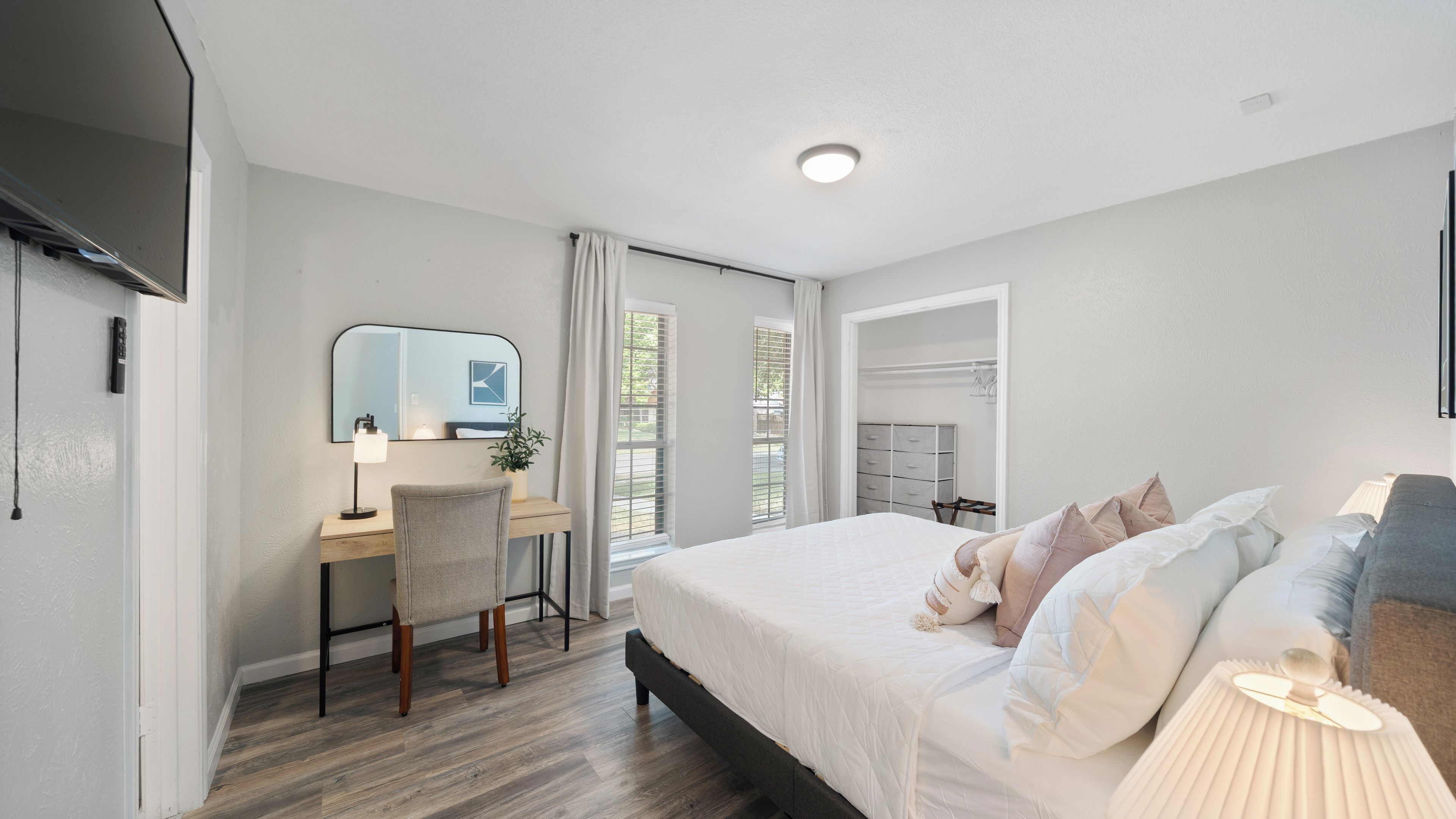 Un dormitorio moderno con cama, escritorio, silla y vestidor.