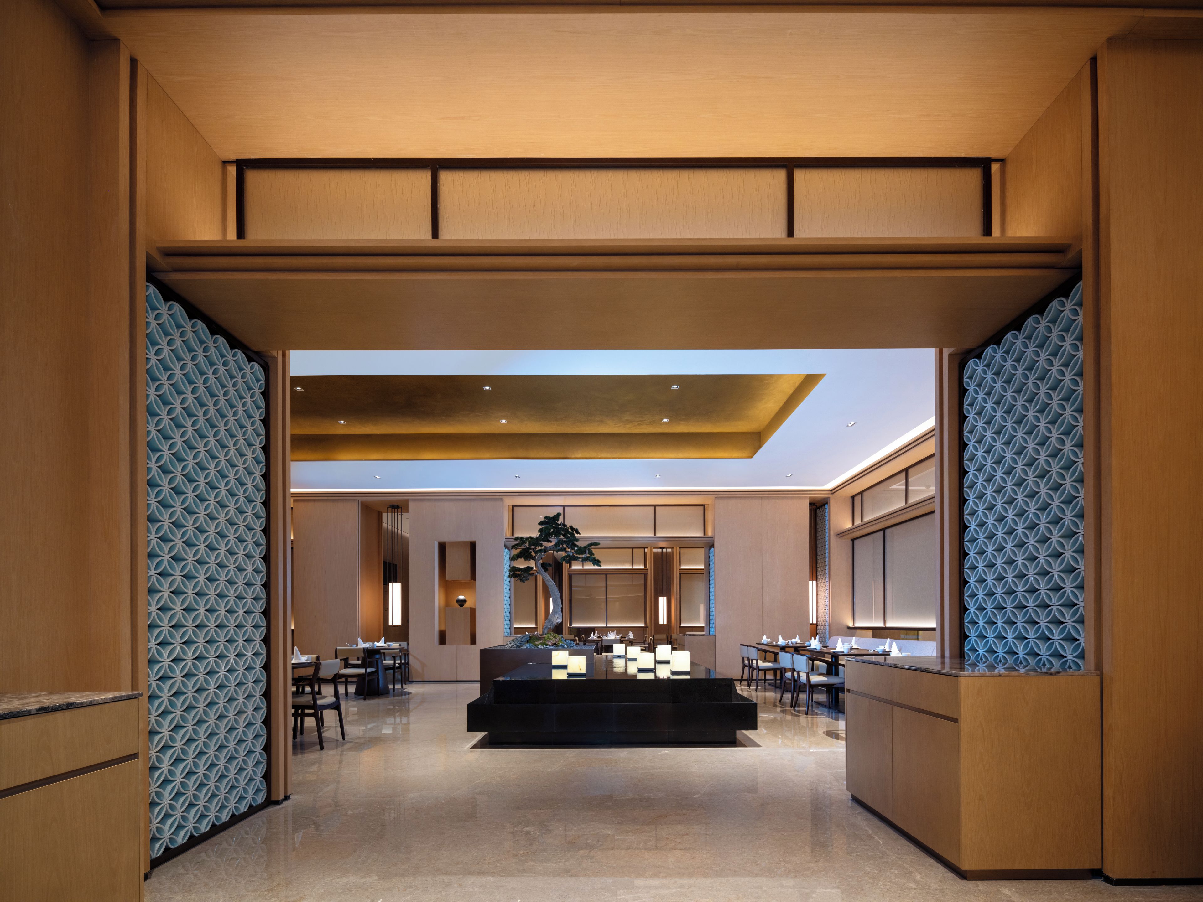 A modern hotel lobby with a reception desk, seating area, and a skylight.