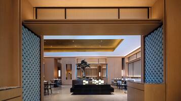 A modern hotel lobby with a reception desk, seating area, and a skylight.