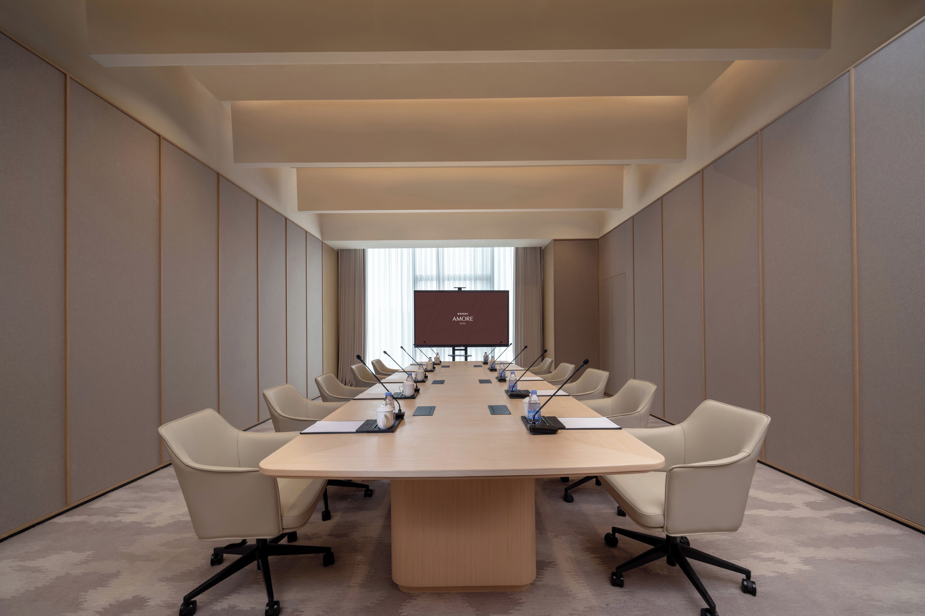 A conference room with a long table, multiple chairs, and a projection screen at the front.