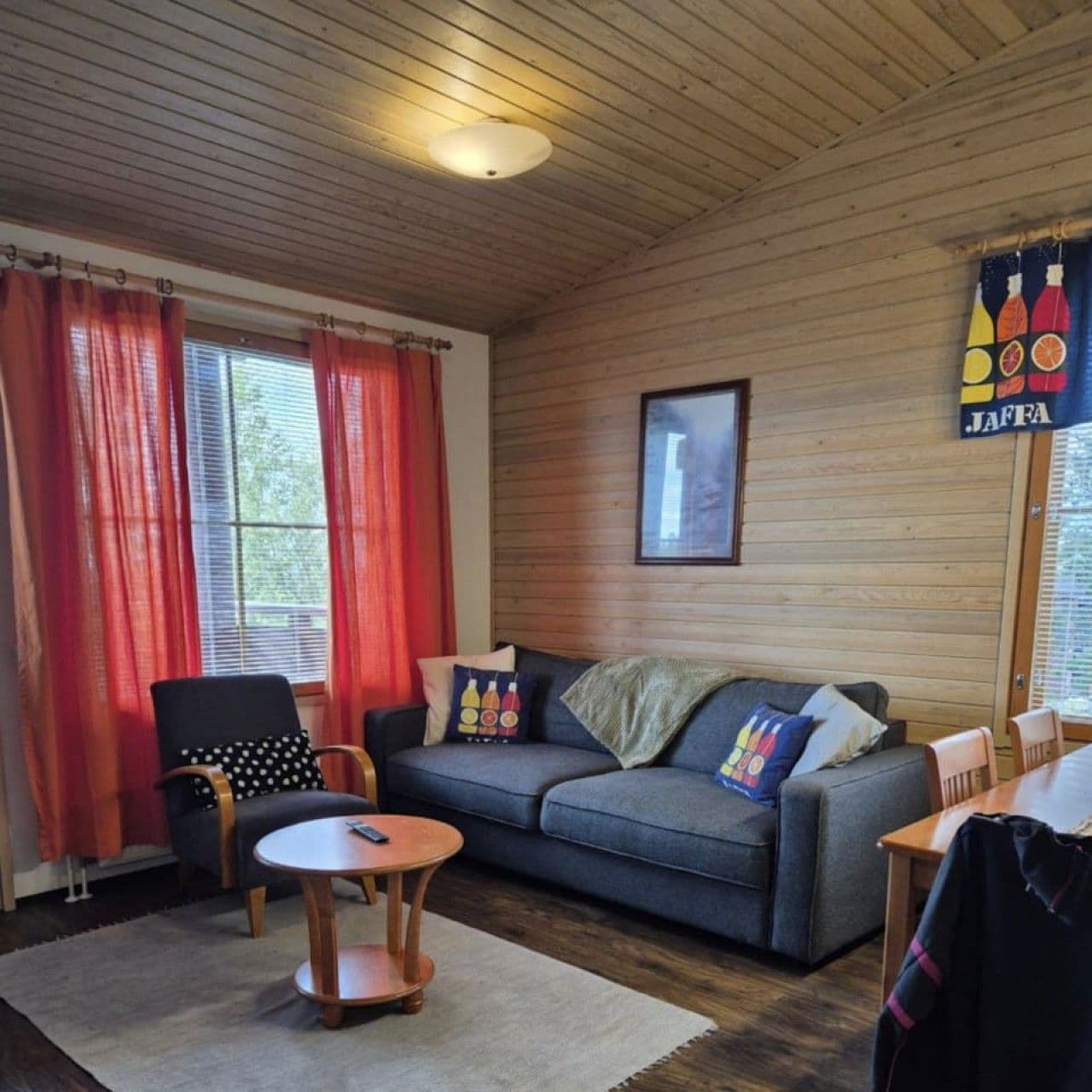 Une pièce chaleureuse avec un plafond en bois, un canapé, une petite table ronde et une chaise.