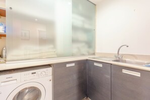 Een kleine wasruimte met een wasmachine, een droogkast en een wasbak.