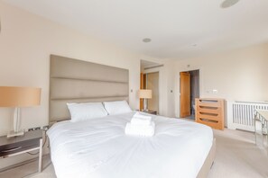 A hotel room with a large bed, bedside tables, a desk, and a wardrobe. - Sleek 3BD flat with Stunning City Views, Vauxhall (London)