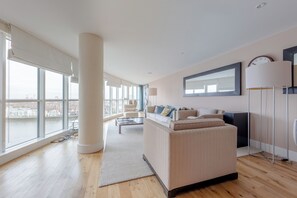 A modern living room with a large window, a sofa, a coffee table, and a floor lamp. - Sleek 3BD flat with Stunning City Views, Vauxhall (London)