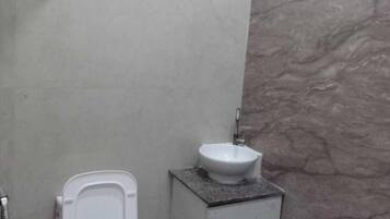 Casa de banho com sanita, lavatório e parede de mármore.
