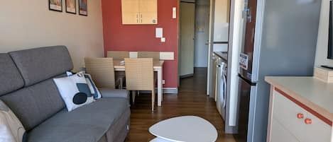 A compact living space with a sofa, a dining table, and a kitchenette area.