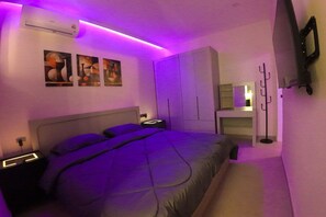 Ein Schlafzimmer mit Bett, Nachttischen, einem Kleiderschrank, einem Spiegel und Wandbildern.