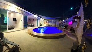 An outdoor swimming pool with a curved edge, surrounded by a patio area with chairs and a table. - Beautiful Private Pool Villa – Perfect Pattaya Escape (Pattaya City)