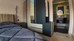 Un dormitorio moderno con una cama grande, una mesita de noche, un espejo y vistas al baño.
