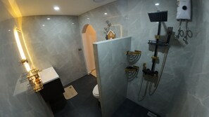 Ein modernes Badezimmer mit Marmorboden, einem weißen Waschbecken, einer Toilette und einer Duschkabine mit Handbrause.