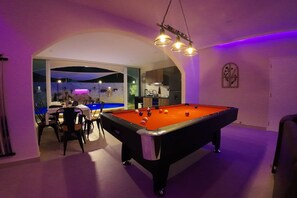 A pool table with a red felt surface, surrounded by chairs, in a room with a purple ambient light. - Beautiful Private Pool Villa – Perfect Pattaya Escape (Pattaya City)
