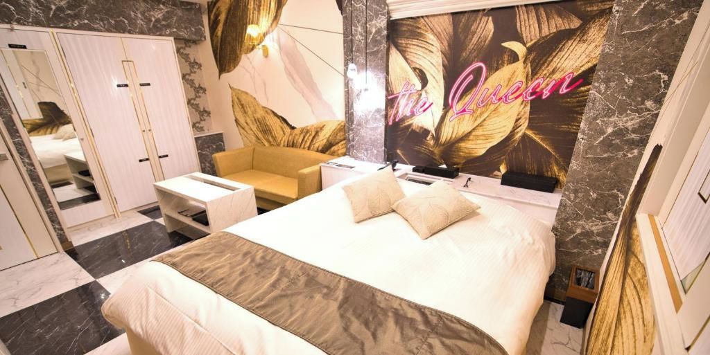 A hotel room with a bed, a sofa, a desk, and a wardrobe.