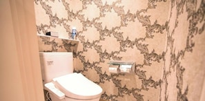 Un baño con inodoro, un estante sobre el inodoro y una pared con diseño.