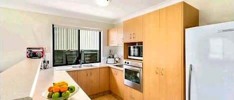 A kitchen with wooden cabinets, a white refrigerator, a microwave, and a stove.