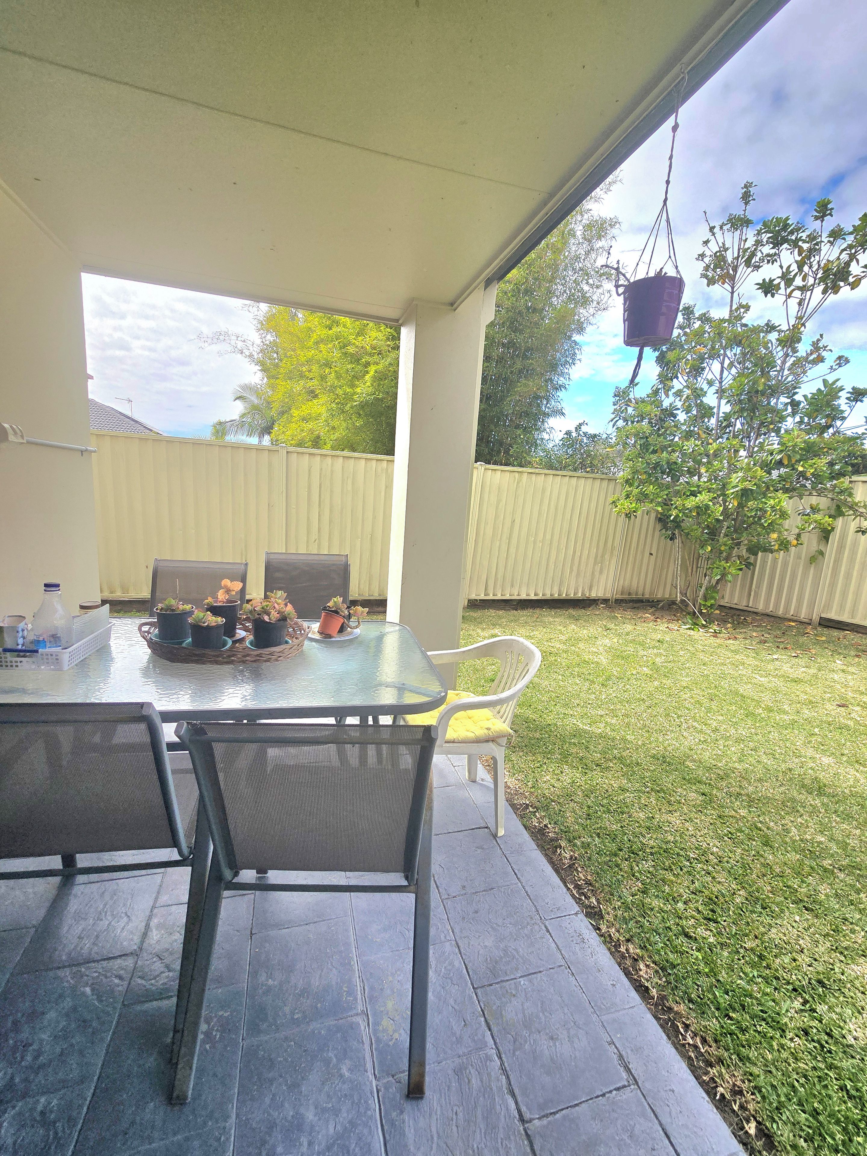An outdoor patio with a table, chairs, and potted plants.