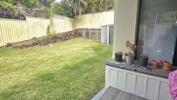 Un espacio al aire libre cubierto con una mesa de patio, plantas en macetas y una jardinera colgante.