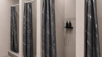 A modern bathroom with three shower stalls, each with a marble-patterned curtain.