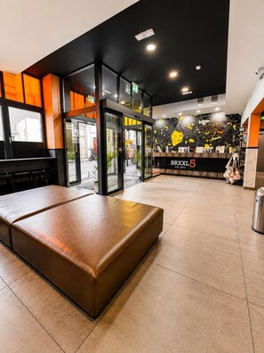 A modern lobby with a seating area, a reception desk, and a wall with a map design. - Brxxl5 City Centre Hostel (Brussels)