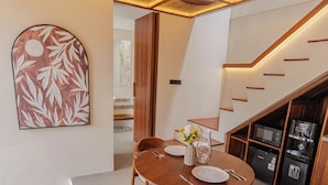 Eine moderne Küche mit Holzschnitzereien, ein Essbereich mit rundem Tisch und Stühlen sowie eine Treppe mit integrierten Geräten.