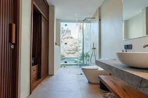 Une salle de bain moderne dotée d’un grand lavabo, de toilettes et d’un espace douche.