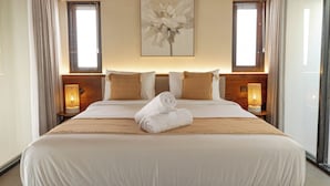 Ein großes Bett mit Holzrahmen, zwei Nachttischlampen und ein großes Blumenbild an der Wand.