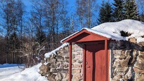 Un edificio de piedra con puerta roja y un pequeño alero.