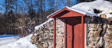 Ein Steinhaus mit roter Tür und einem kleinen Vordach.