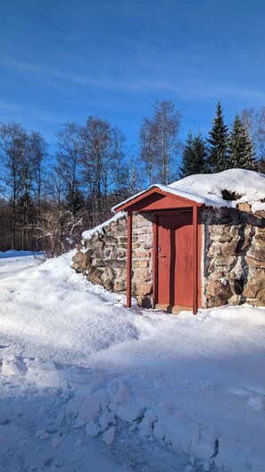 A stone building with a red door and a small overhang. - Vintage Elegance - Swedish Cottage From 1909 (Markaryd)