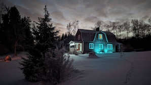 Una casa grande de madera con un porche y un patio cubierto de nieve.
