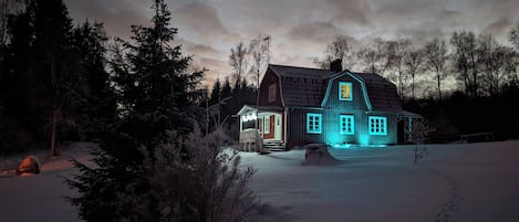 Una casa grande de madera con un porche y un patio cubierto de nieve.