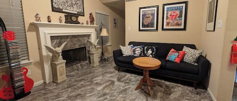 A living room with a fireplace, a black sofa, and a coffee table.