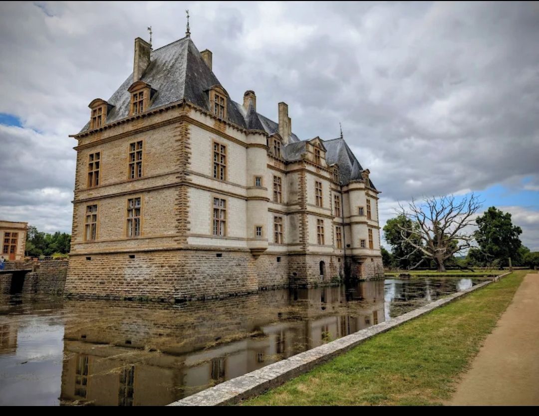 Un bâtiment historique entouré de douves, doté de plusieurs niveaux et d’une tour imposante.