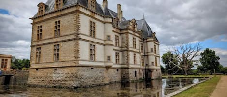 A historic building with a moat, featuring multiple levels and a prominent tower.