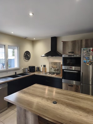 A modern kitchen with a central island, built-in appliances, and a large window.
