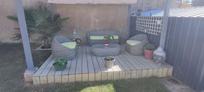 A patio with wicker furniture, a small table, and potted plants.