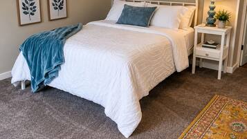 A bedroom with a bed, bedside table, lamp, and a rug.