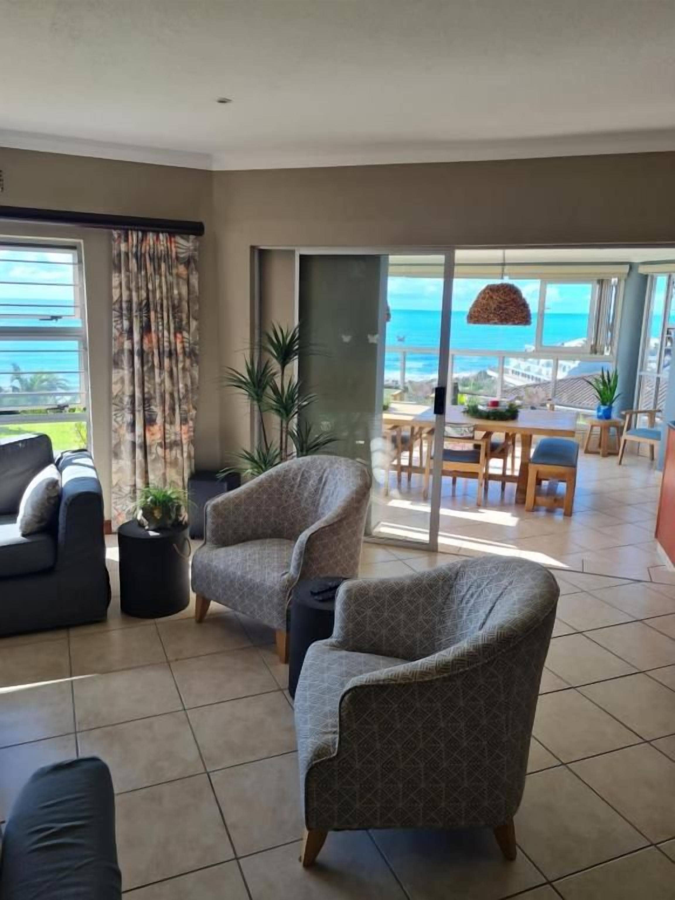 A living room with a sofa, armchairs, and a dining area with a table and chairs.