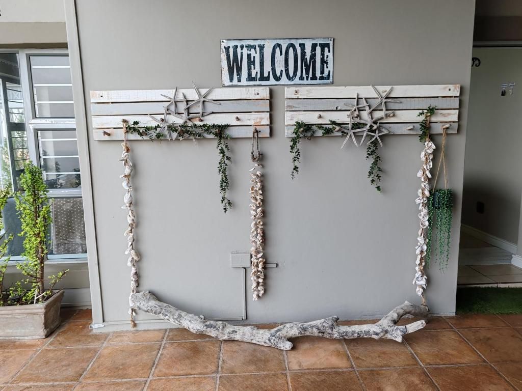A welcome sign with wooden planks and starfish decorations against a wall.