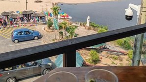 Strandudsigt fra en balkon med et bord i forgrunden.