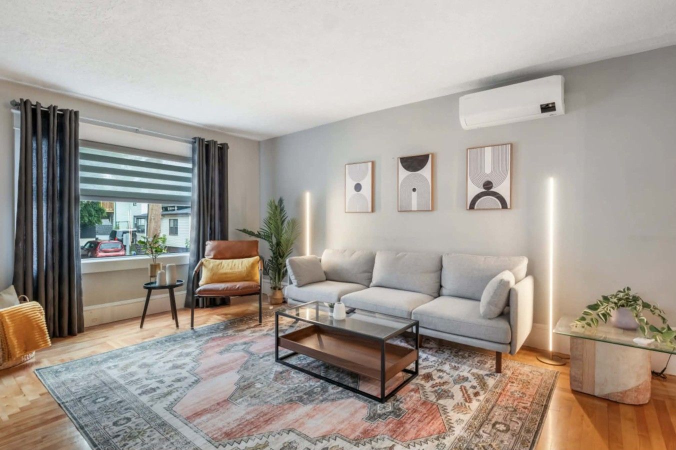 Una sala de estar moderna con un sofá, un sillón, una mesa de centro y un amplio ventanal con cortinas.