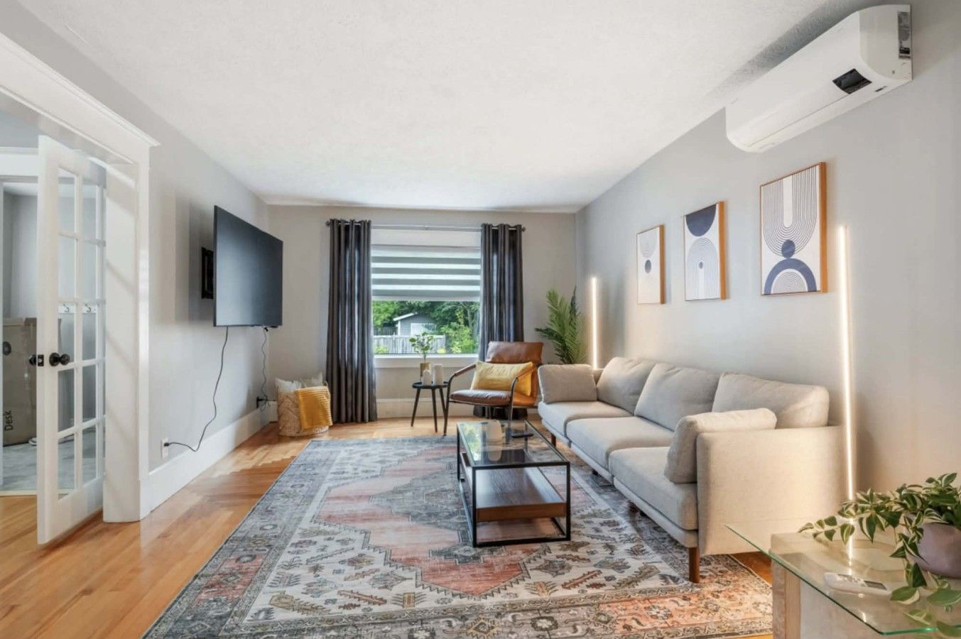 Un salon moderne avec un canapé, une table basse et un téléviseur fixé au mur.